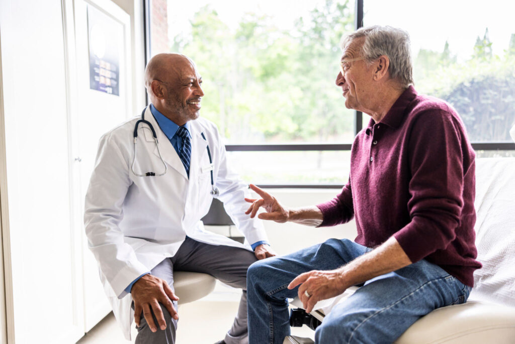 Male doctor talking with senior man in exam room